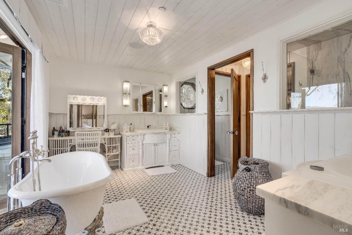 The freestanding soaking tub and spacious shower create a spa-like ambiance, while the elegant vanity and chandelier add a touch of glamour. The white and black checkered floor tiles provide a classic and timeless feel, completing this opulent bathroom retreat.