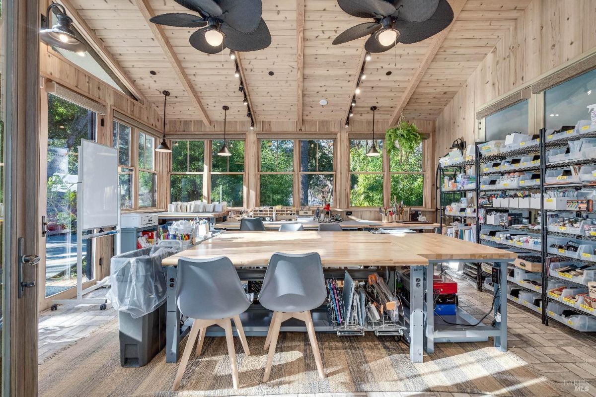 With ample natural light streaming through the windows, a large workspace, and plenty of storage for supplies, it's an ideal studio or workshop. The wood-paneled ceiling and neutral color palette create a calming atmosphere, while the pops of greenery add a touch of life and vibrancy.