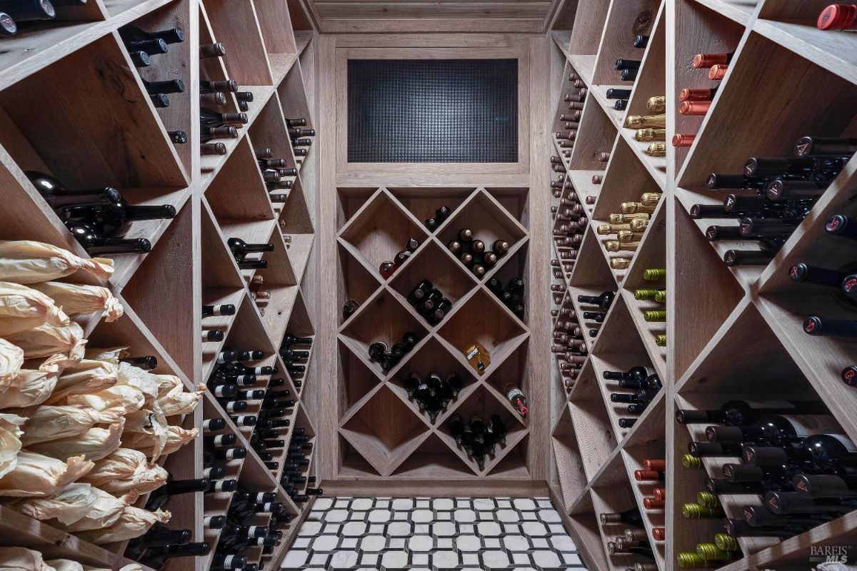 Temperature-controlled wine cellar is a haven for any wine enthusiast. The custom-built wooden racks cradle a vast collection of bottles, while the diamond-shaped compartments and the checkered floor tiles add visual interest. 