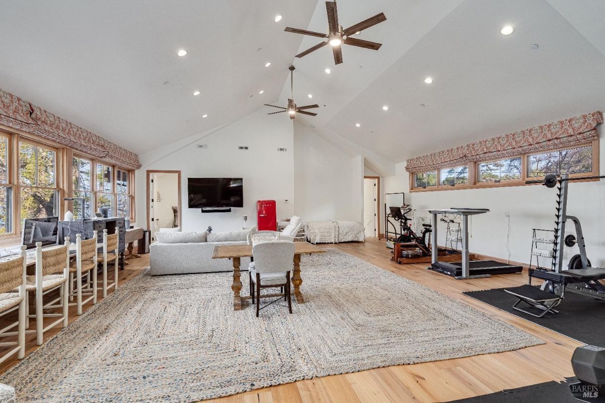 With distinct zones for fitness, work, and relaxation, it caters to a variety of needs. The vaulted ceilings and abundant natural light enhance the spaciousness, while the neutral color palette and comfortable furnishings create an inviting atmosphere.