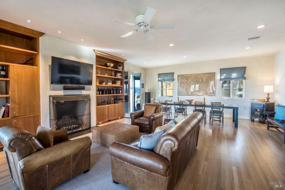 Cozy family room features leather seating, a fireplace, and built-in shelves for storage and decor.