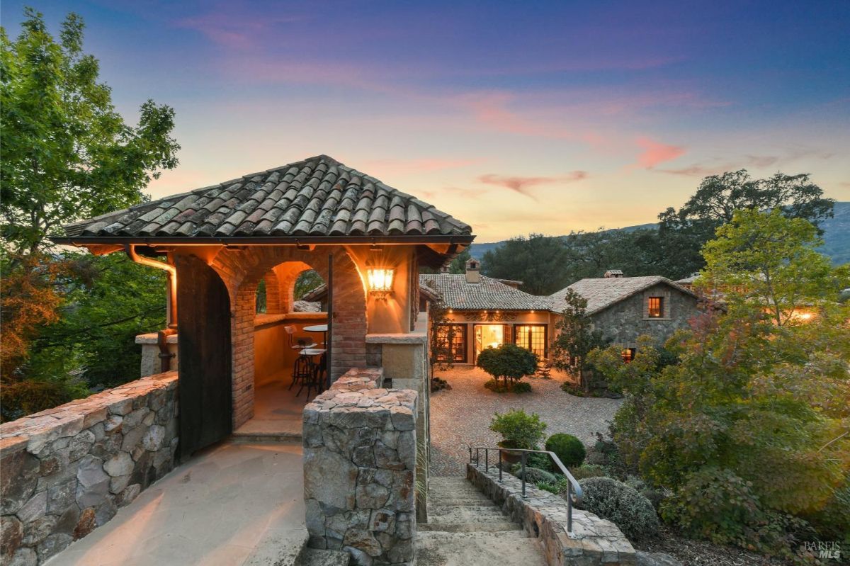 Rooftop terrace with an outdoor seating area overlooking a cobblestone courtyard and the surrounding landscape.