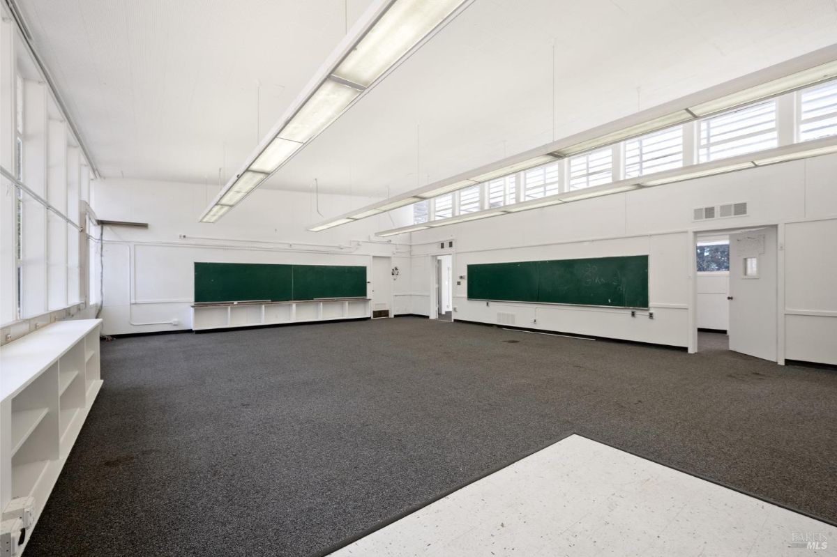 Spacious classroom with large windows, fluorescent lights, and blackboards on the walls.