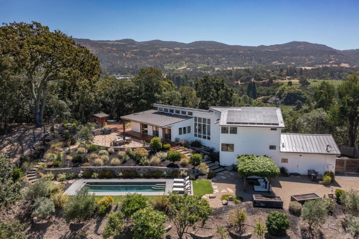 A hillside home with a pool and landscaped gardens.