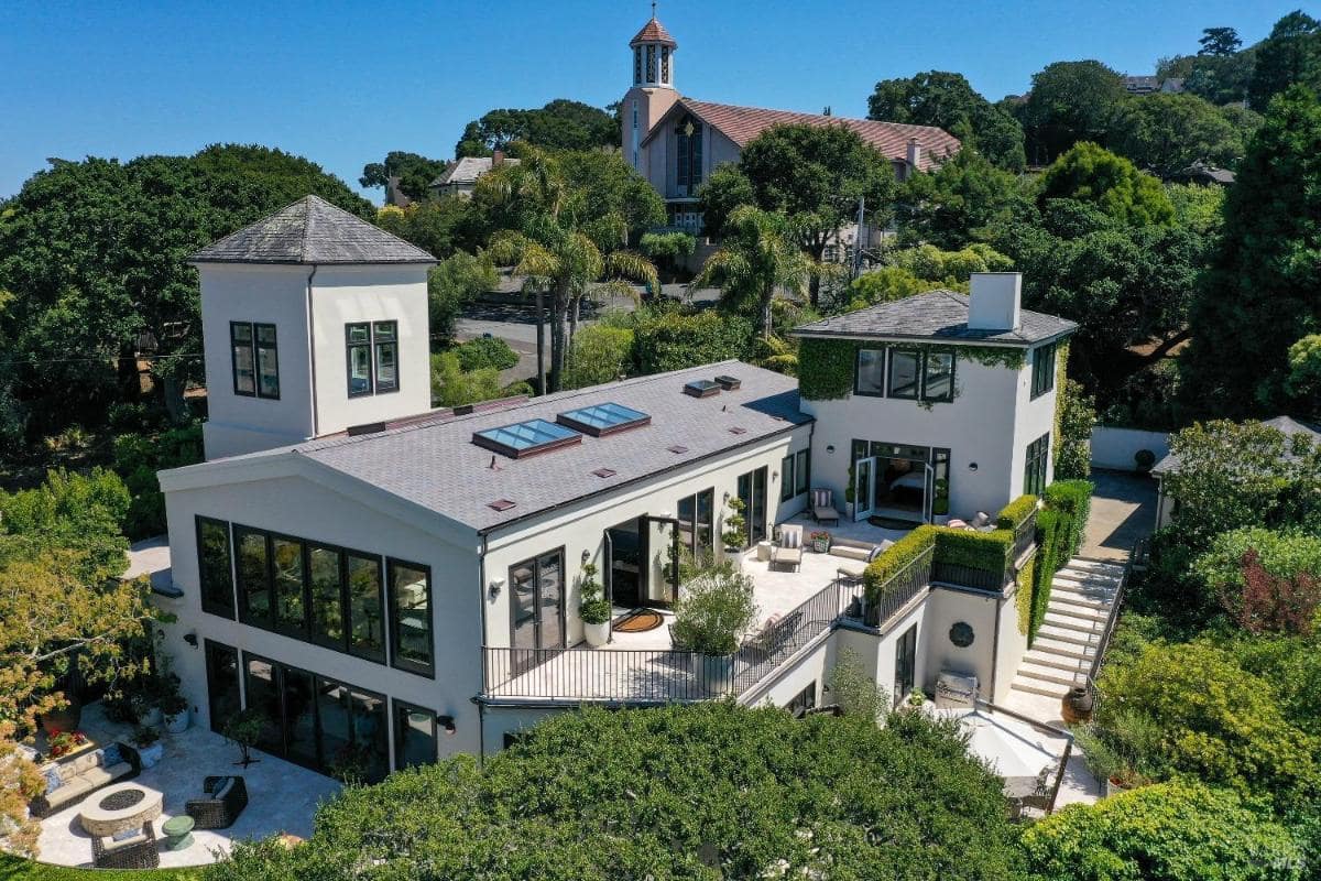 Aerial view of a contemporary house with a landscaped yard and surrounding greenery.