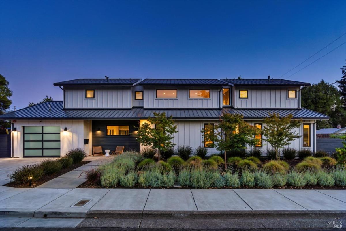 Modern two-story home with a metal roof and landscaped front yard.