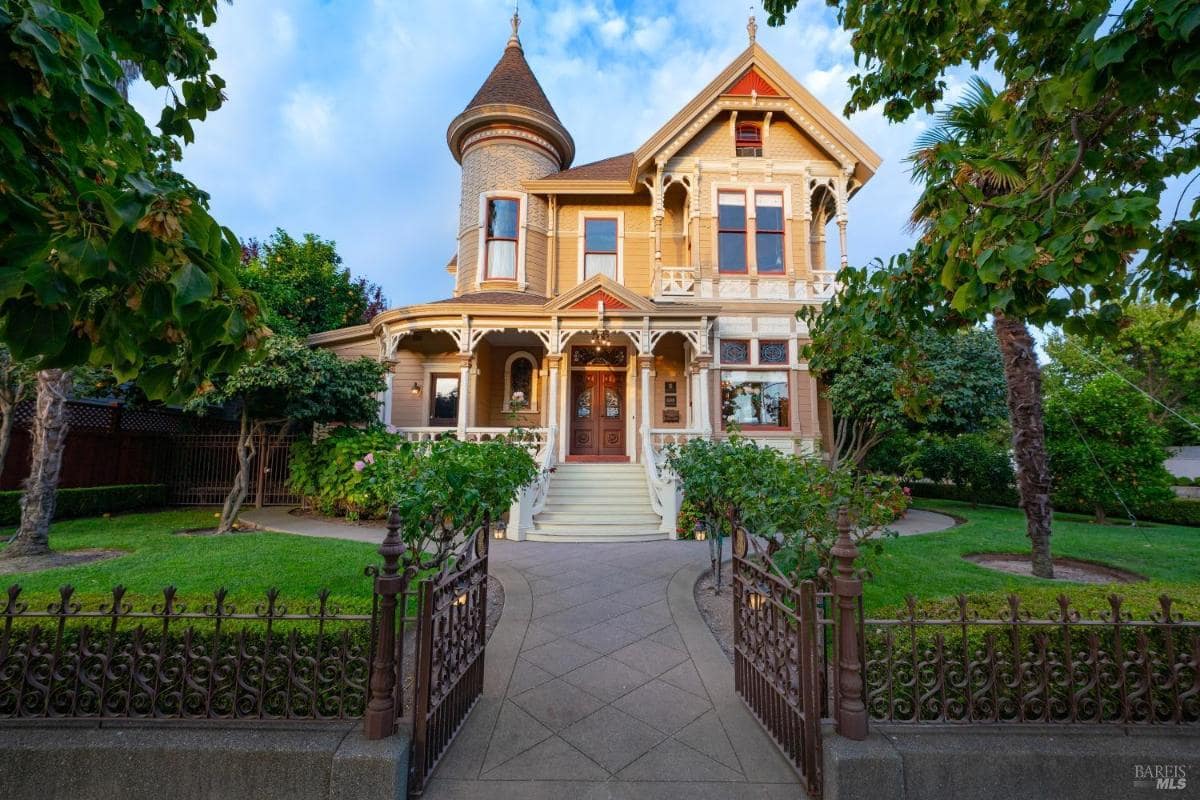 A Victorian-style house with a wraparound porch and ornate design.