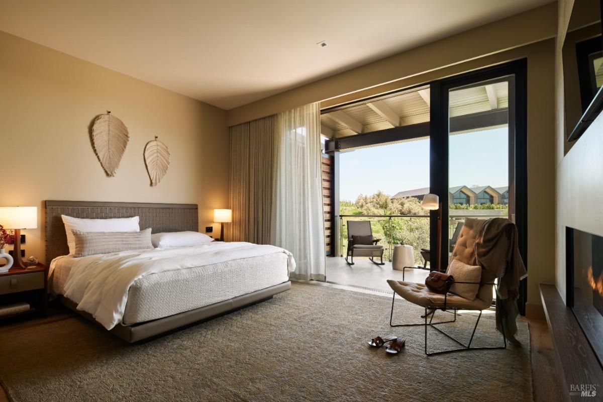 A bedroom with a bed, two nightstands, and a sliding glass door leading to a balcony.