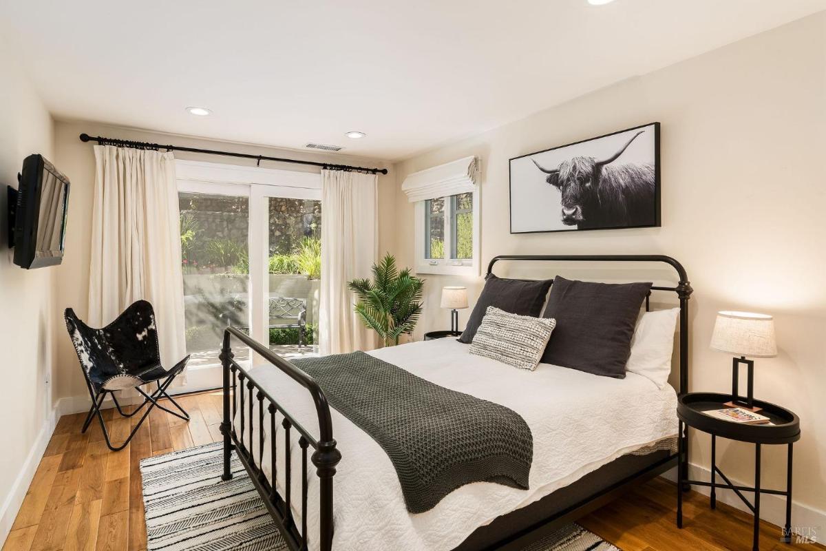 A bedroom with a bed, TV, and a chair near a sliding glass door.

