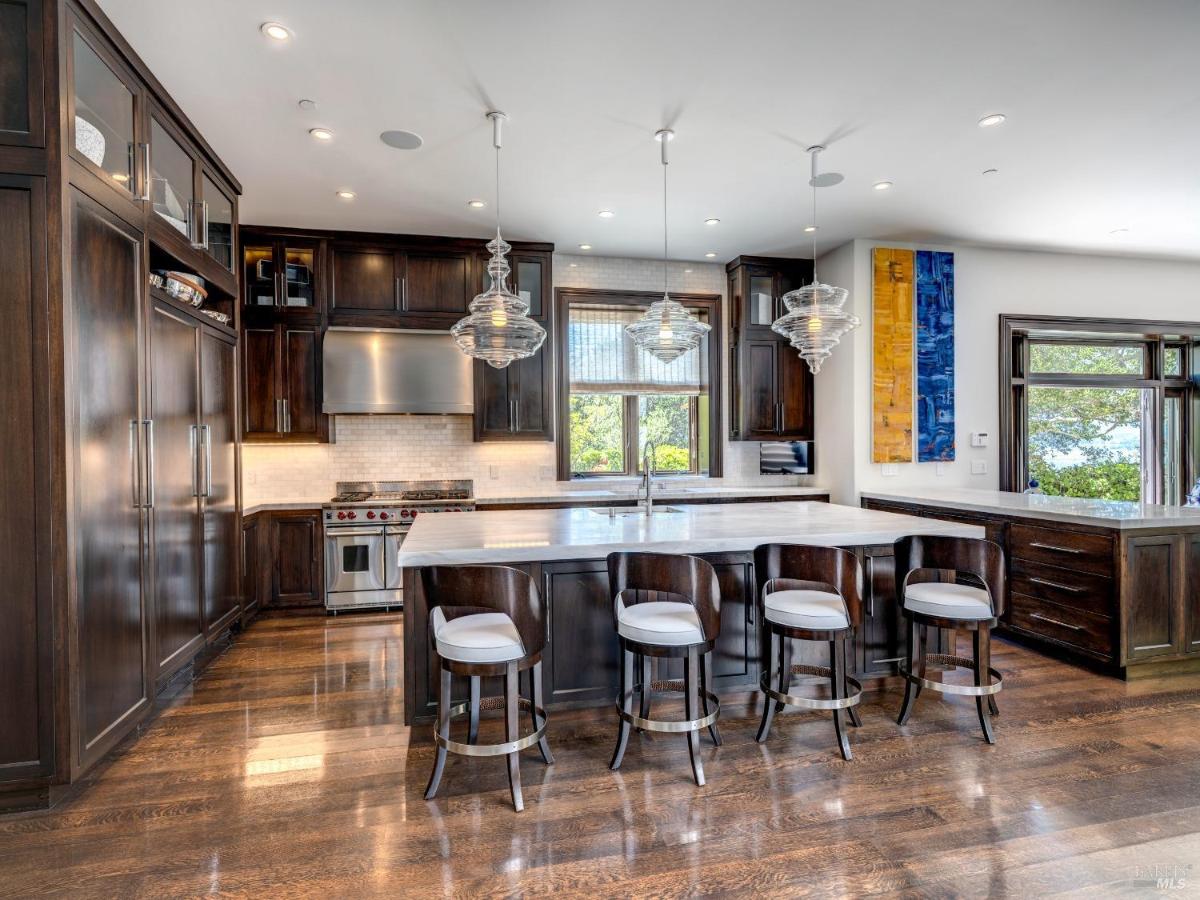 Kitchen with a large island, dark cabinetry, and stainless steel appliances.