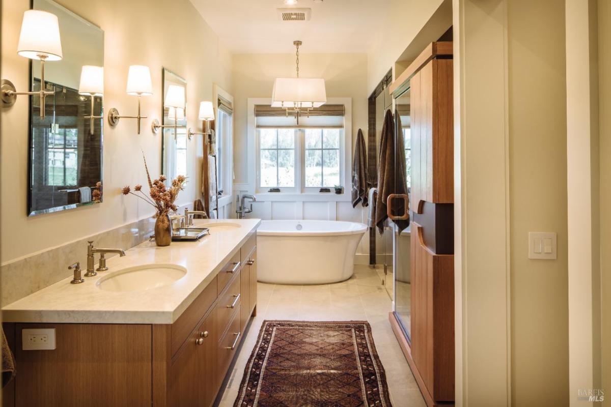 A bathroom featuring a double vanity, freestanding bathtub, and large windows.