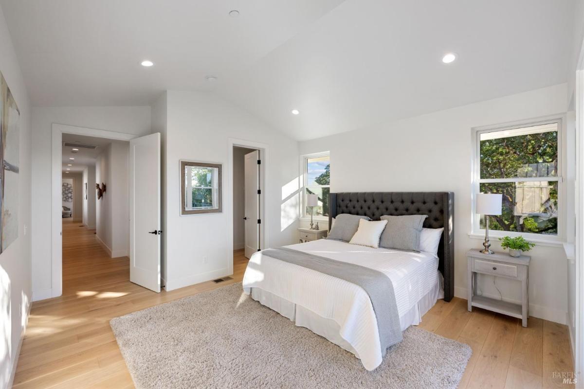 Bedroom with a tufted headboard, nightstands, and large windows.