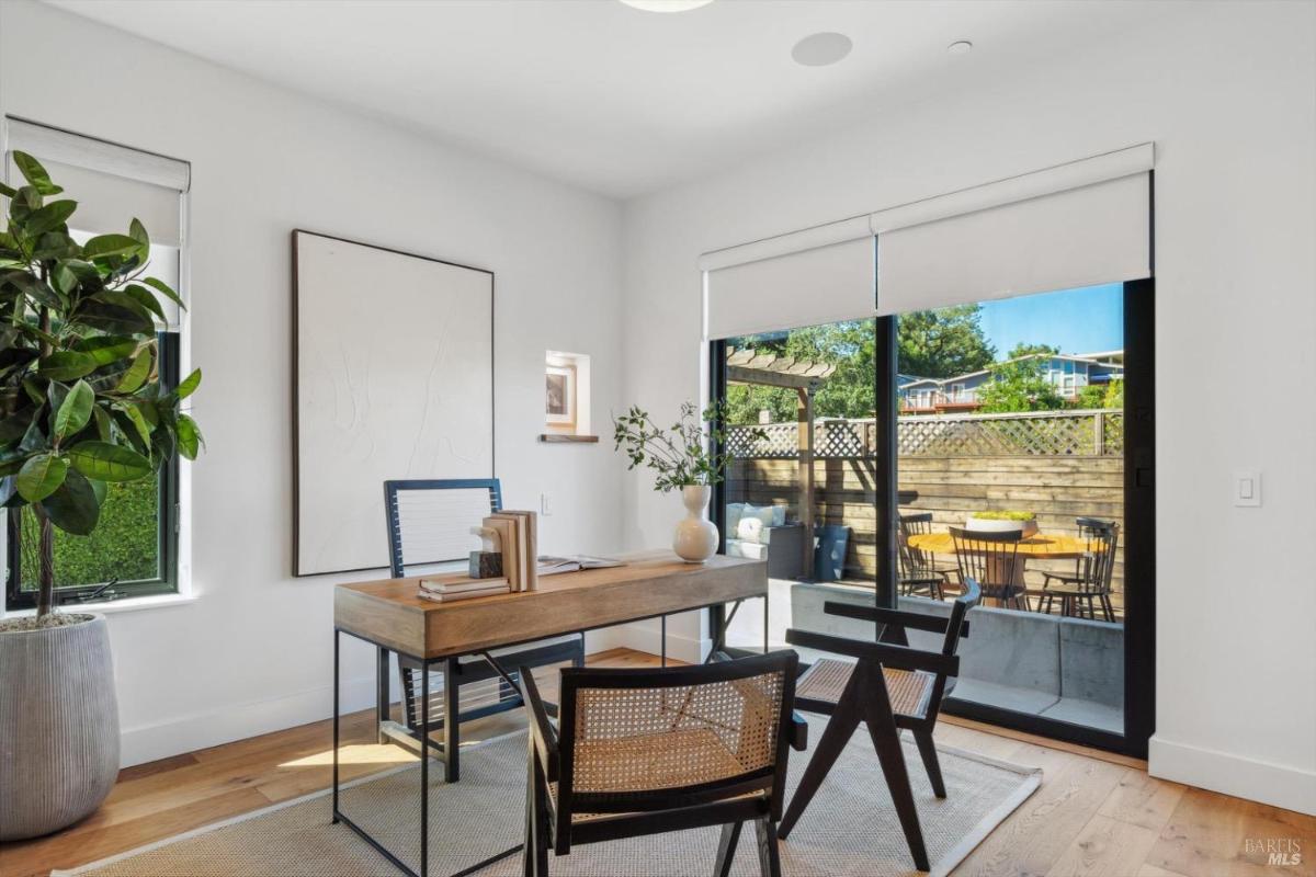 Home office with a desk, chairs, and sliding glass doors to an outdoor patio.