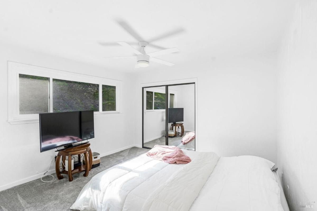 Bedroom with mirrored closet doors and a wall-mounted TV.