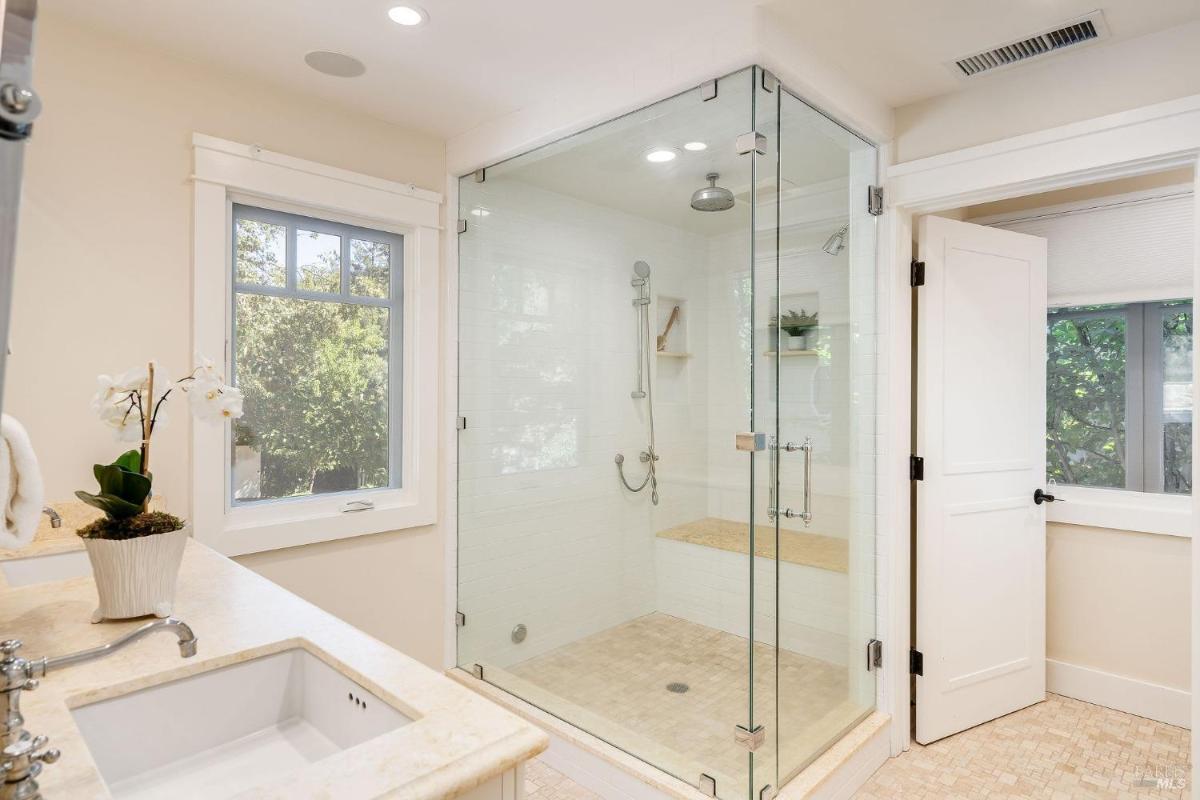 A bathroom featuring a glass shower and a sink.

