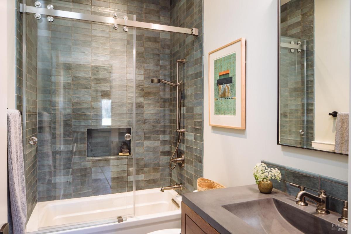 A bathroom with a tiled shower and a vanity with a single sink.