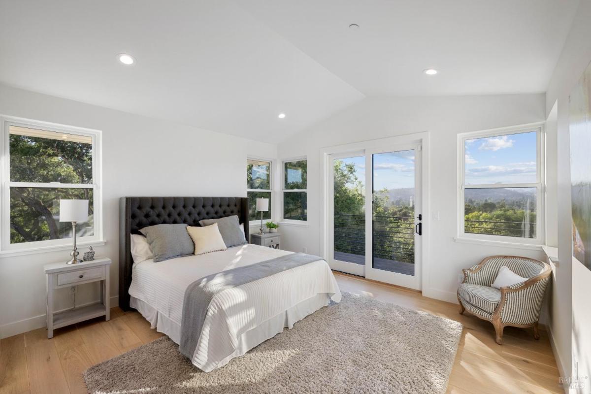 Bedroom with a door to a balcony overlooking greenery.