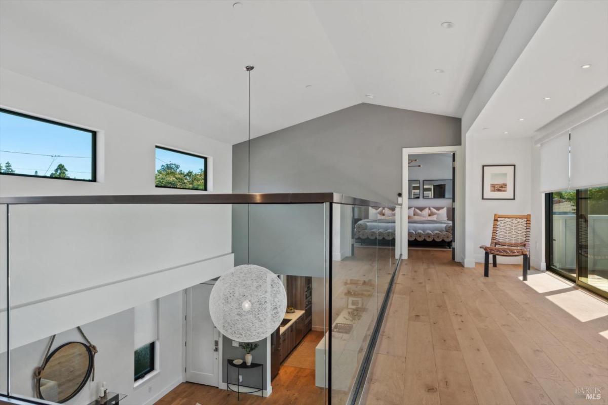 Hallway with a glass railing and view of the open floor below.