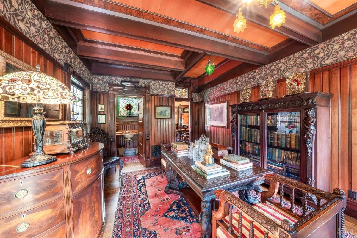 A wood-paneled library with built-in bookshelves and a coffered ceiling.