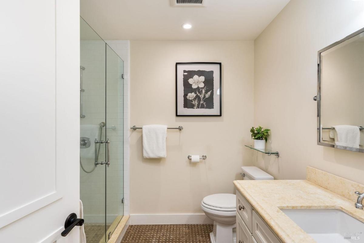 A bathroom with a glass shower, toilet, and sink.

