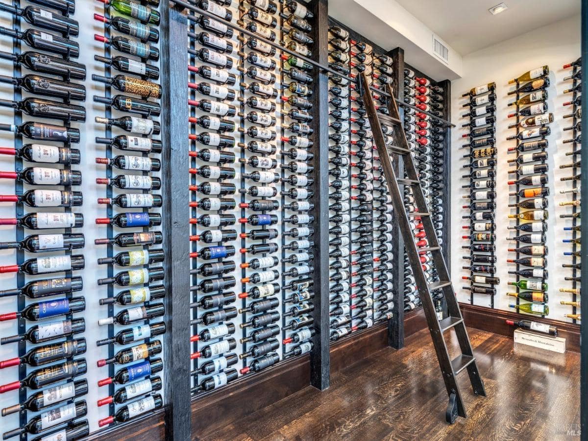 Wine room with multiple racks and a ladder for access.