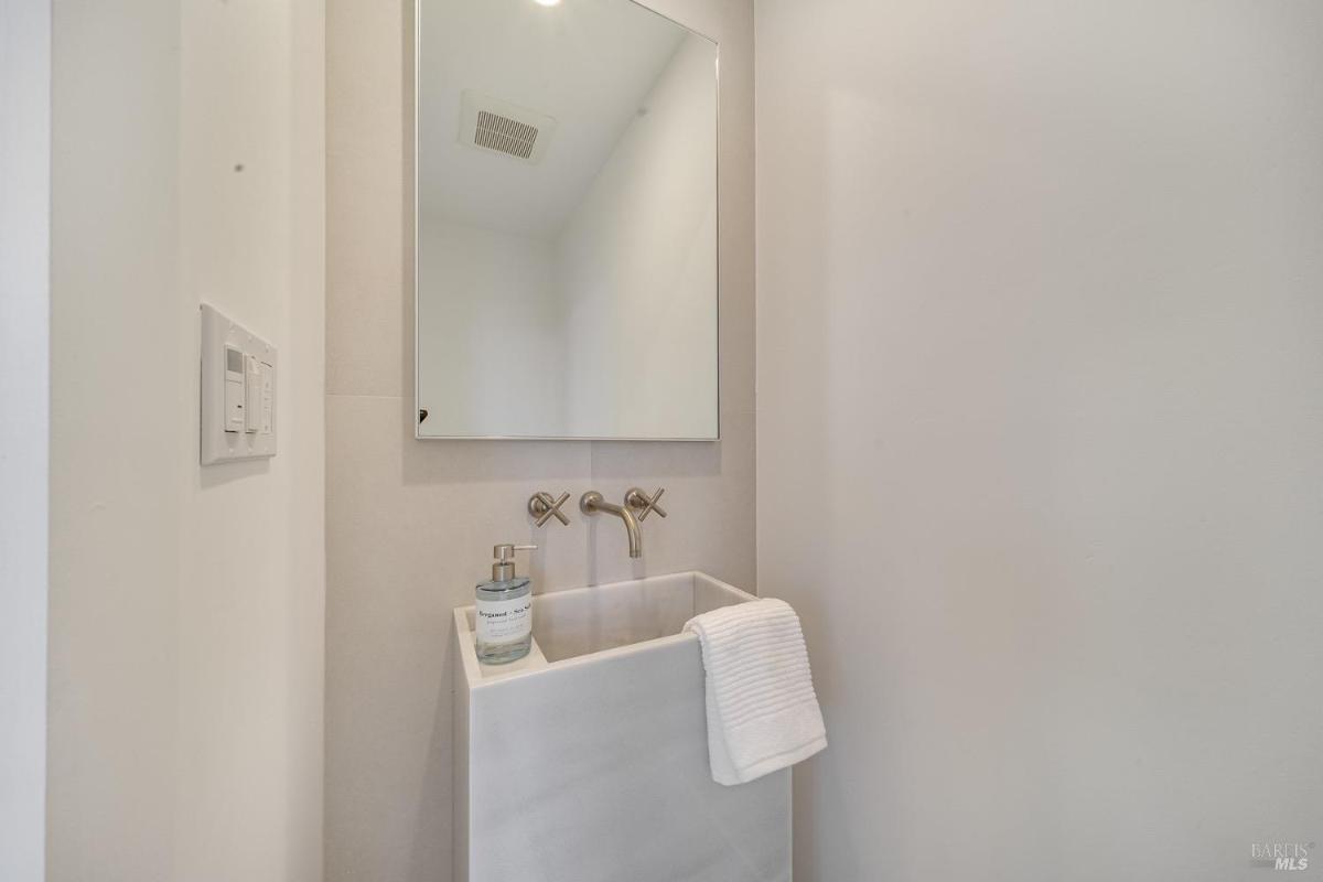 A small sink with a wall-mounted mirror in a compact powder room.