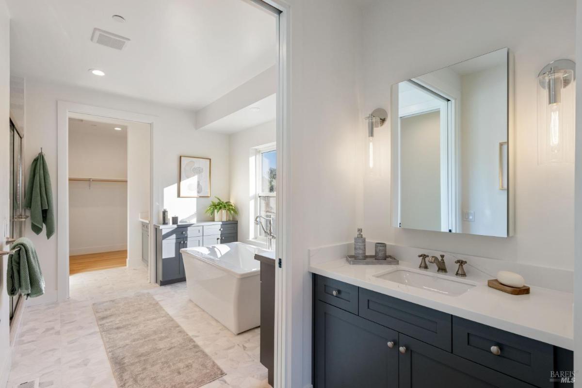 Bathroom with dual sinks, a freestanding bathtub, and a walk-in closet.