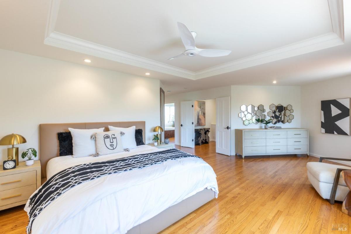 A bedroom with a king-size bed, recessed lighting, and access to a connected room.