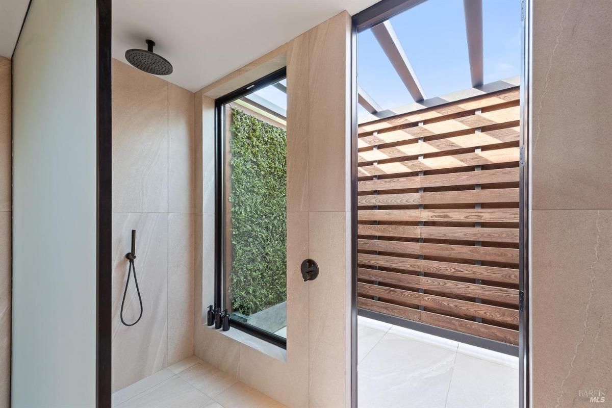 A shower with glass doors and a view of an outdoor privacy wall.