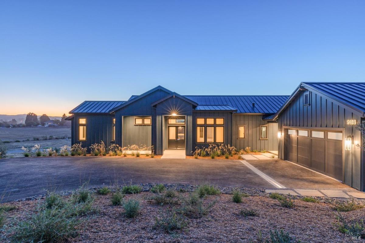 A house with an extended driveway and surrounding landscaping.