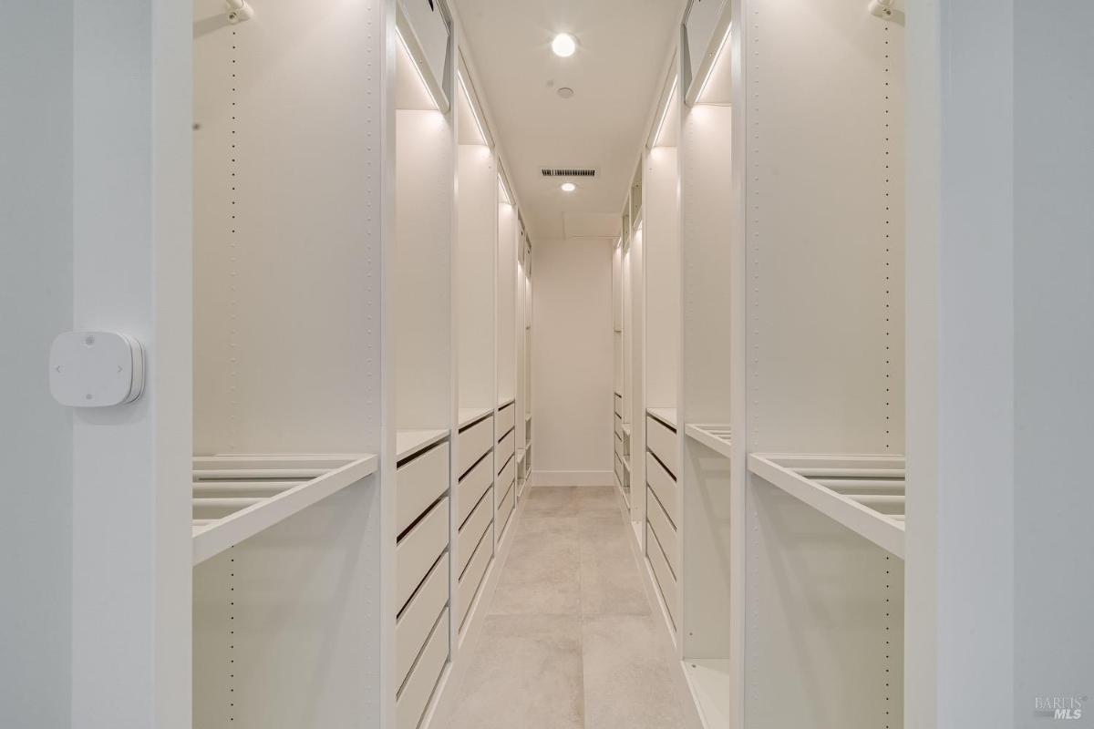 A walk-in closet with built-in shelving and drawers along both sides.