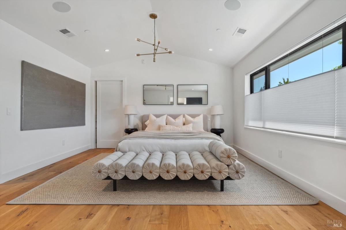 Bedroom with a modern bed, plants, and an attached bathroom visible.