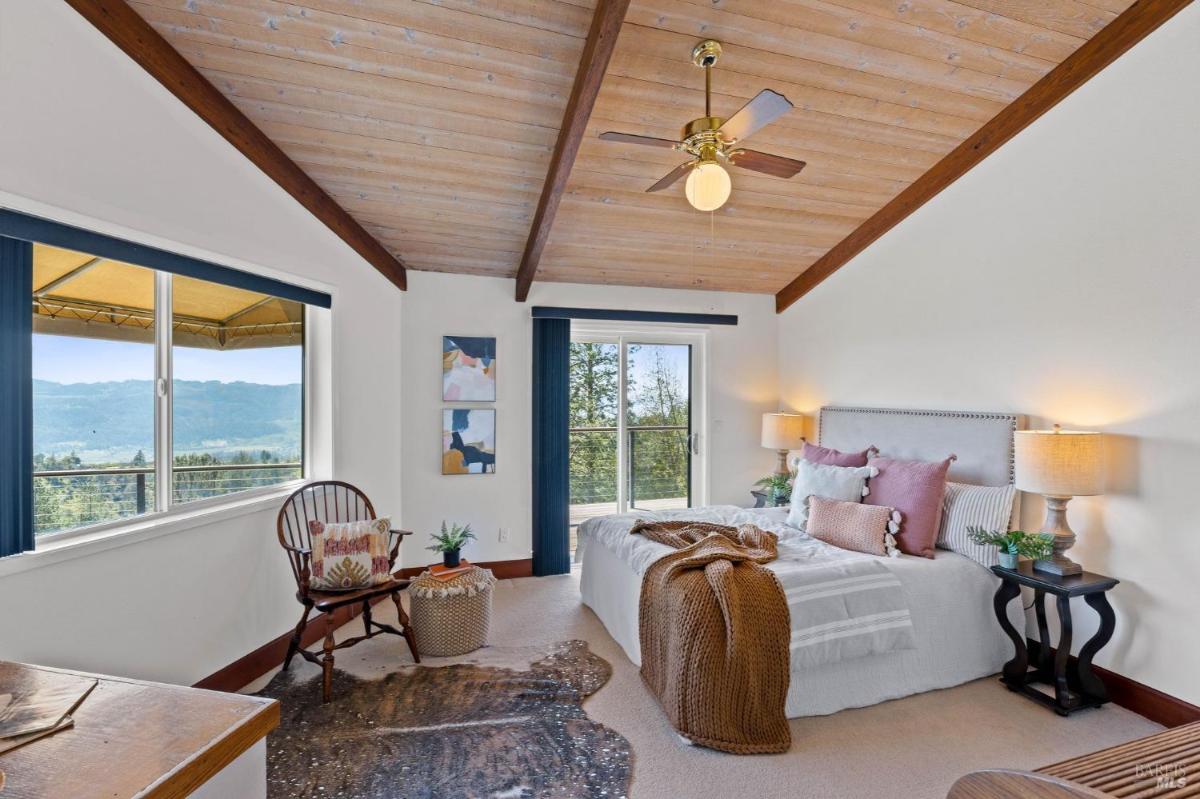 Bedroom with sloped wooden ceilings and a window overlooking the landscape.