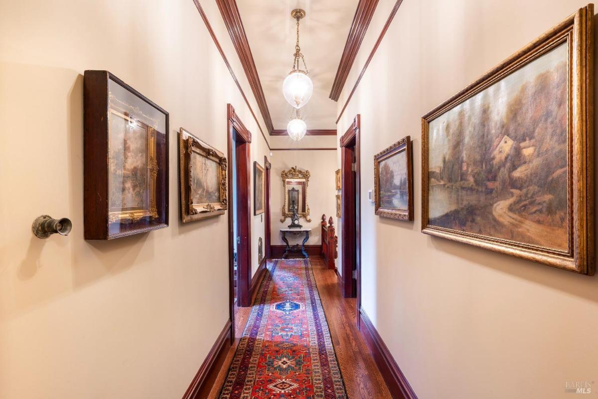 A hallway lined with framed artwork and a red carpet runner.