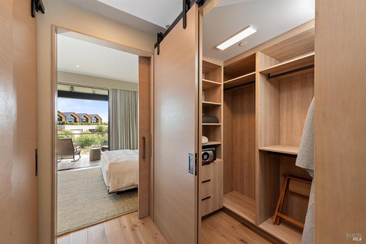 A walk-in closet with wooden shelves and a sliding door to the bedroom.