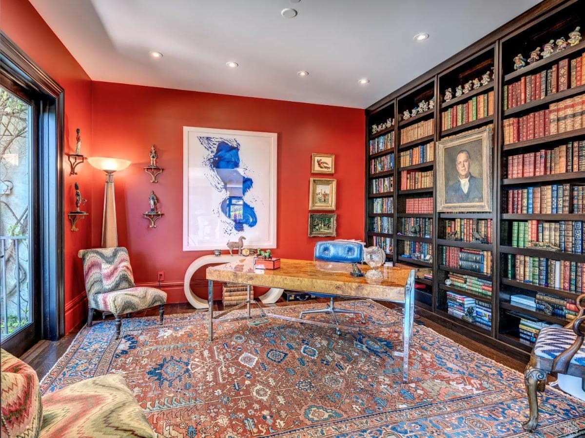 Library with red walls, built-in bookshelves, and a central desk.