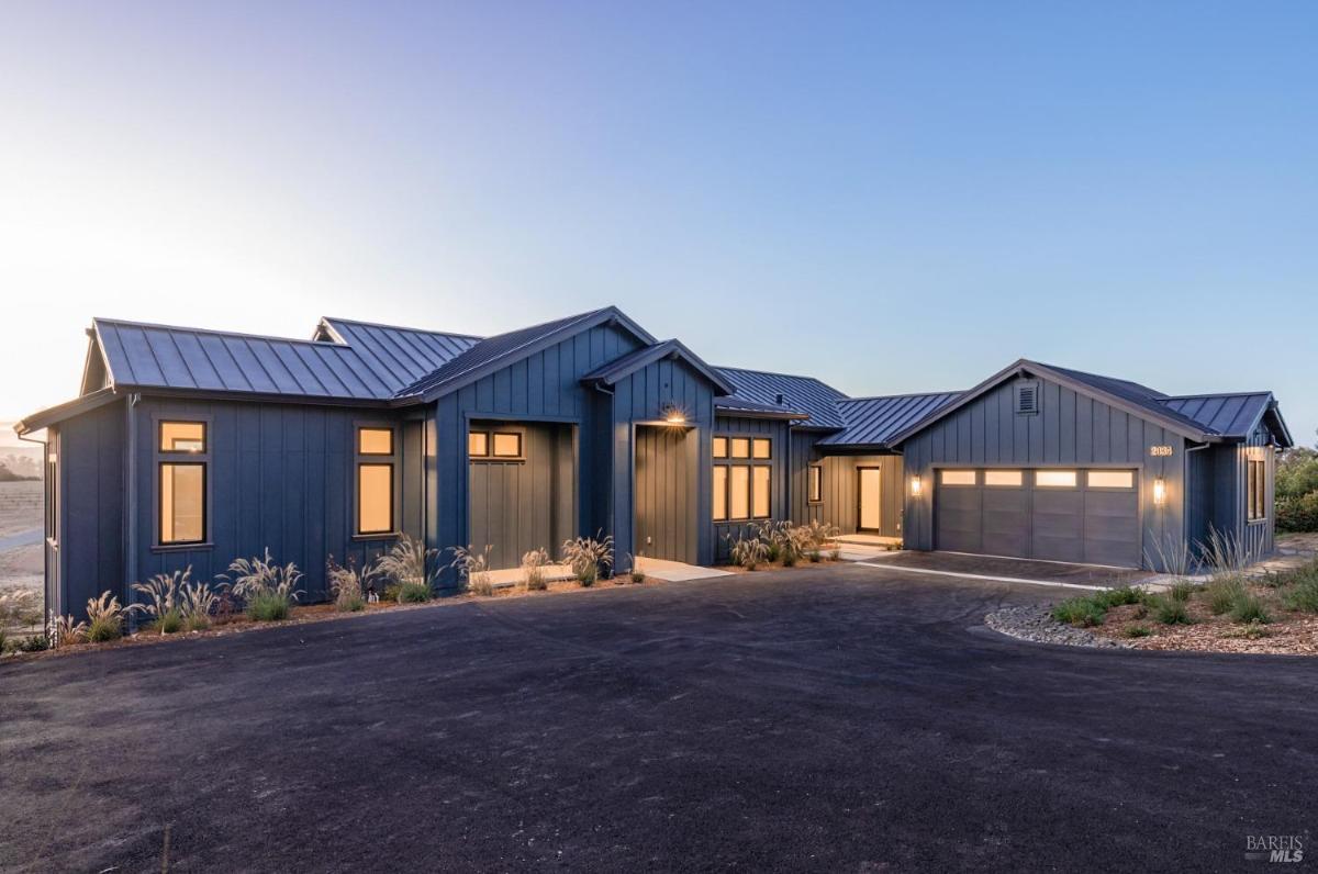 A house with an extended driveway and surrounding landscaping.