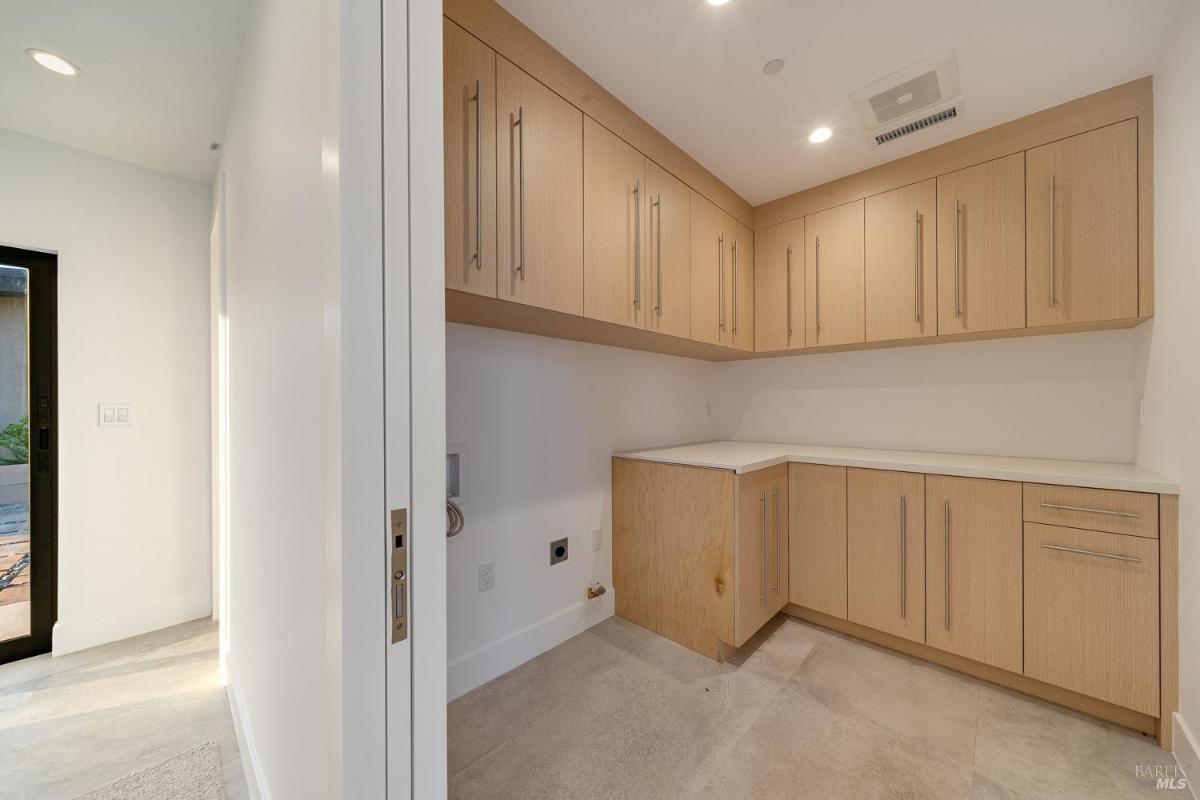 A laundry room with wooden cabinets and countertop workspace.