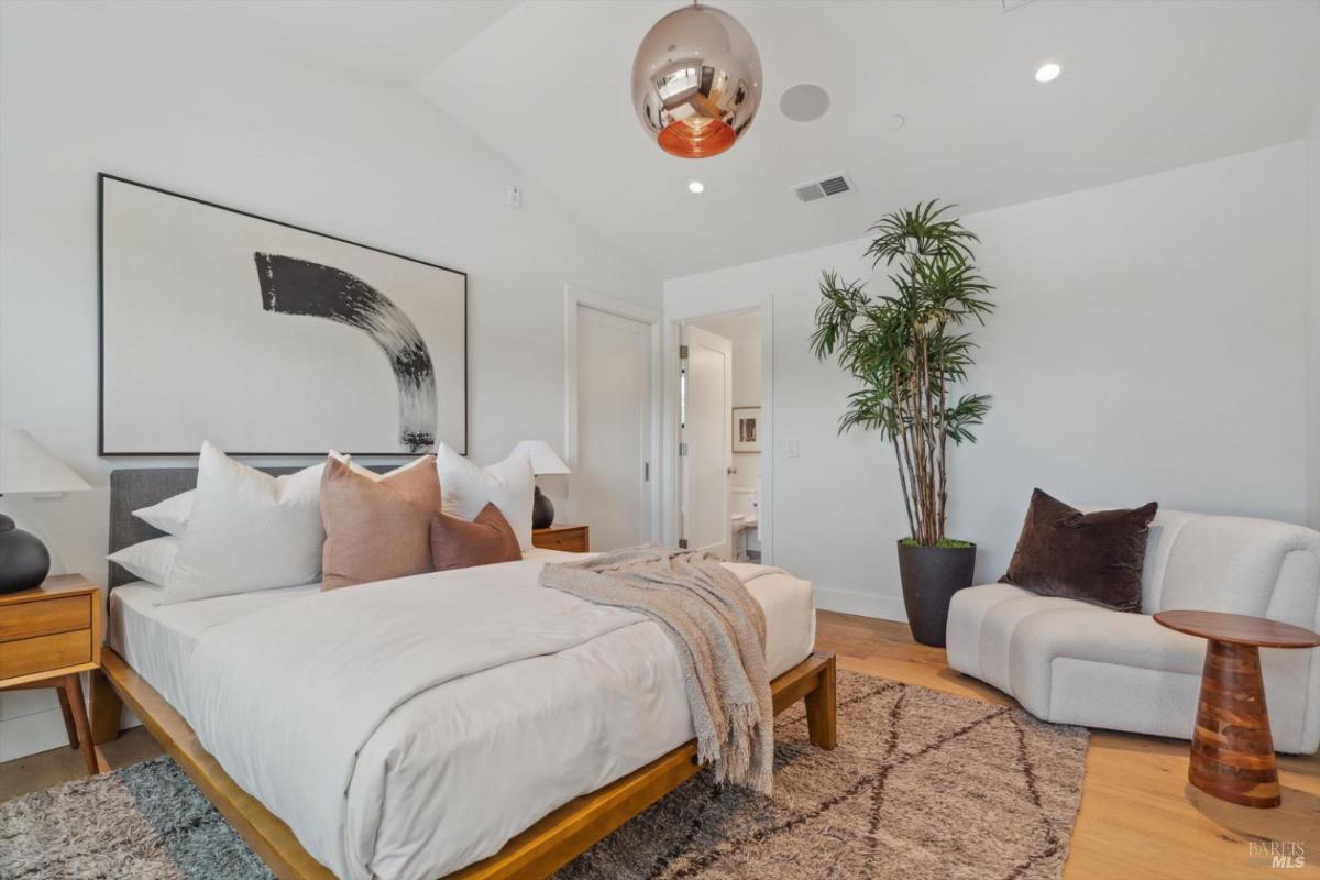 Bedroom with a bed, large mirrors, and natural lighting from windows.