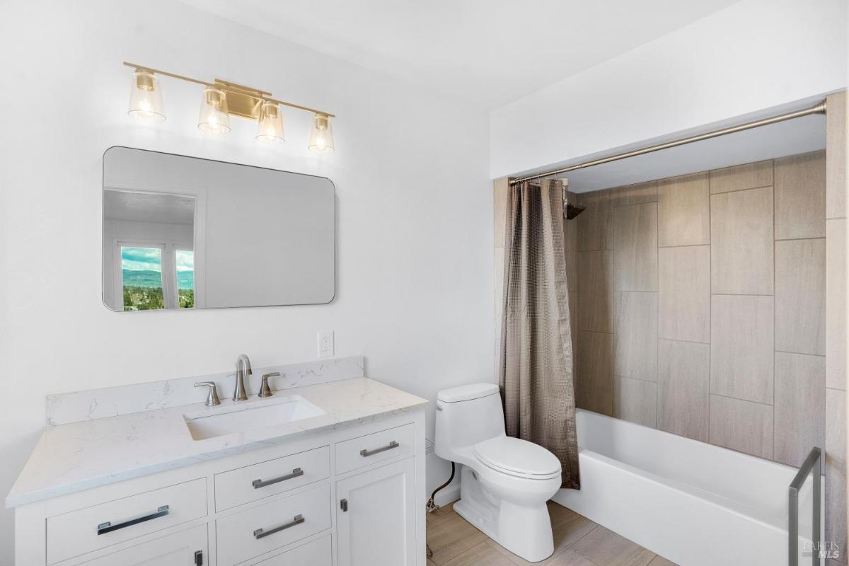 Bathroom with a single sink vanity and a bathtub with shower curtain.