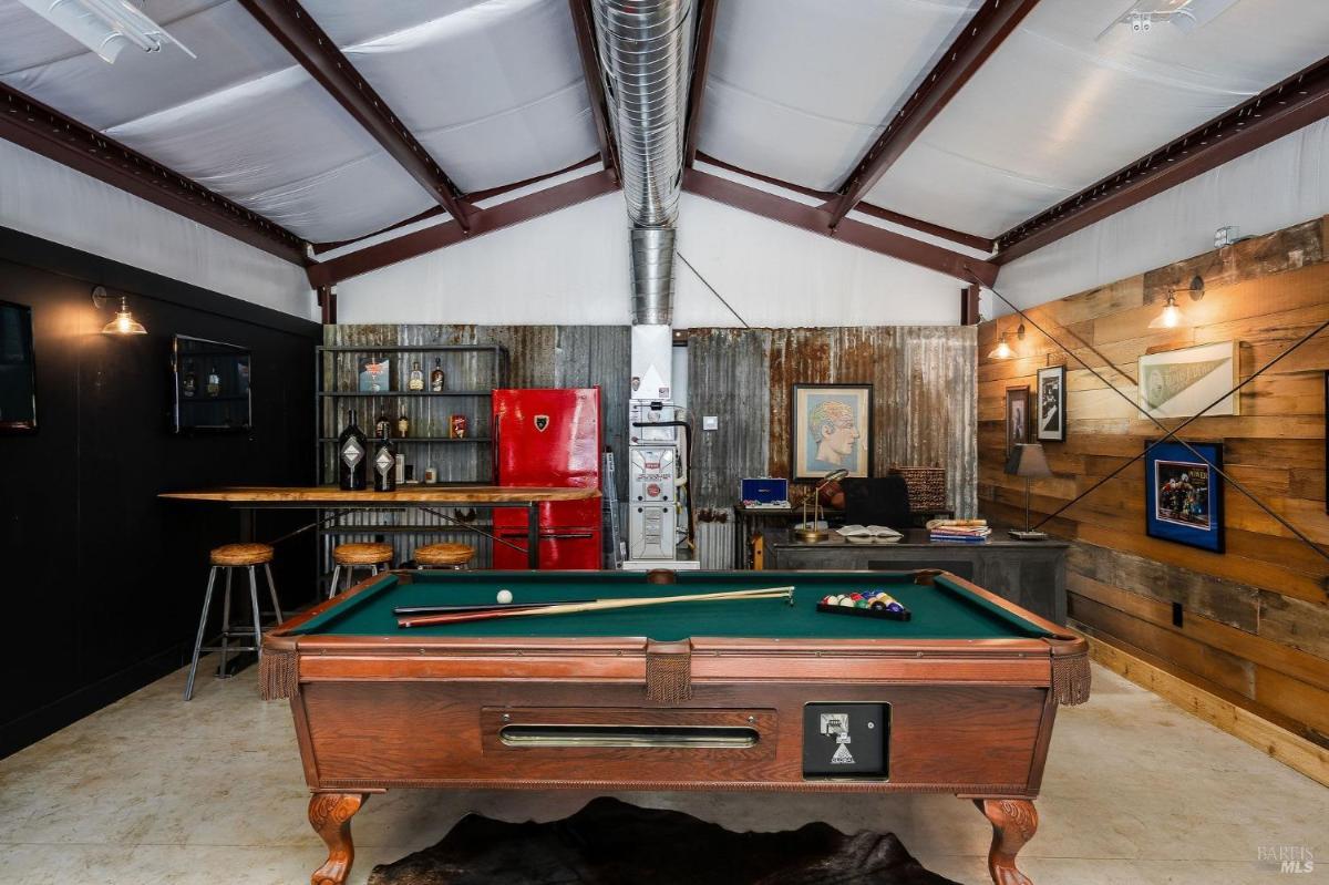 A pool table is in a recreational room with metal and wood accents.

