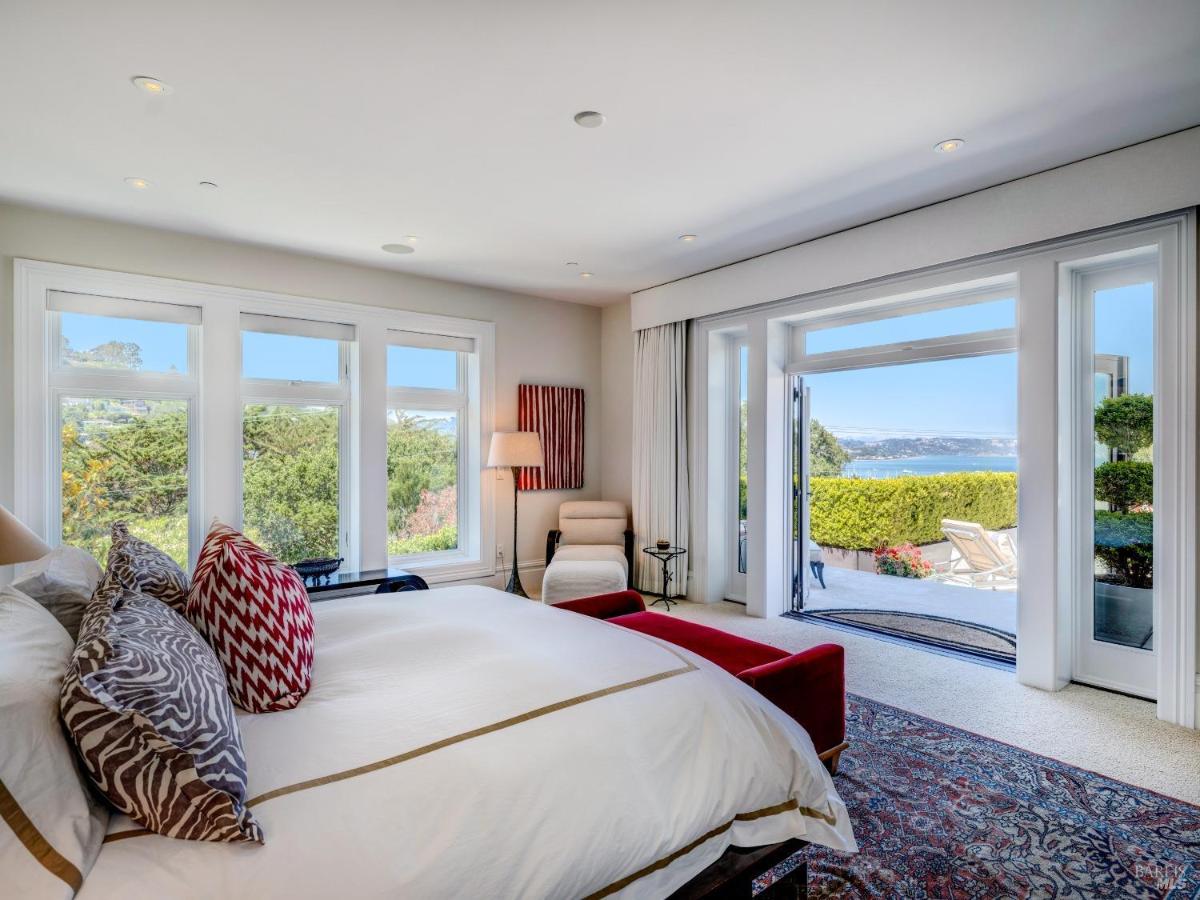 Bedroom with a large bed, sitting area, and doors opening to a patio.