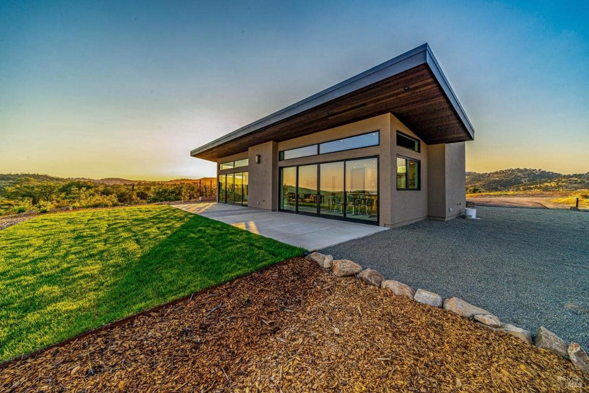 An exterior view of a modern home with large windows and landscaped surroundings.