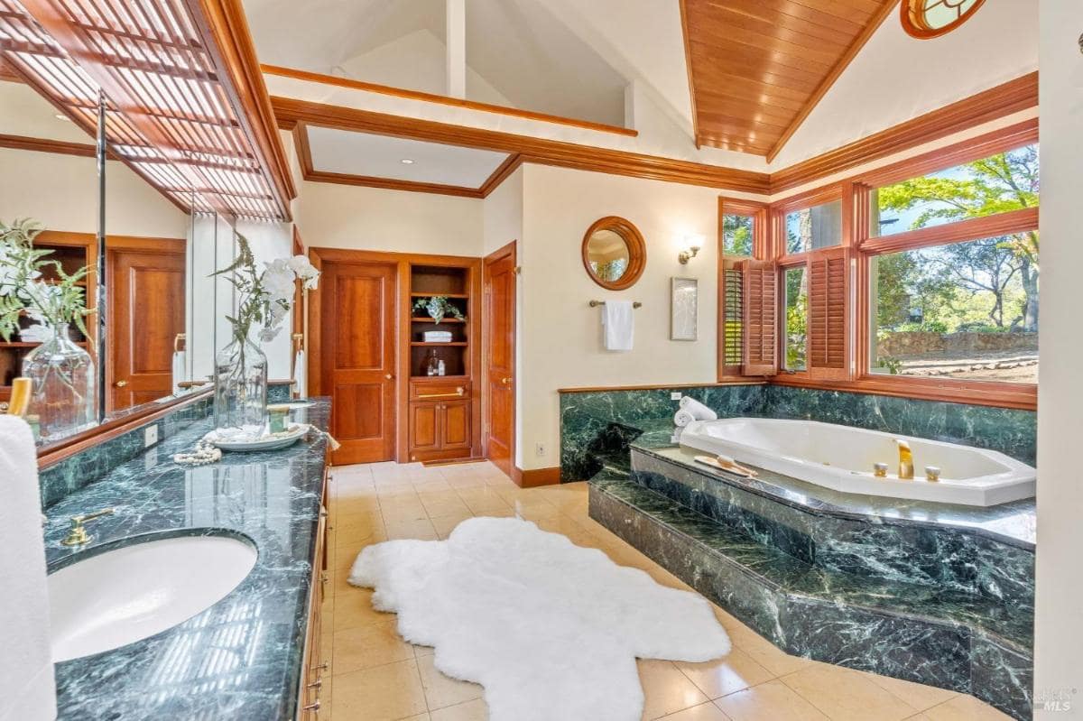 Bathroom with a green marble tub, matching counters, and wooden accents.