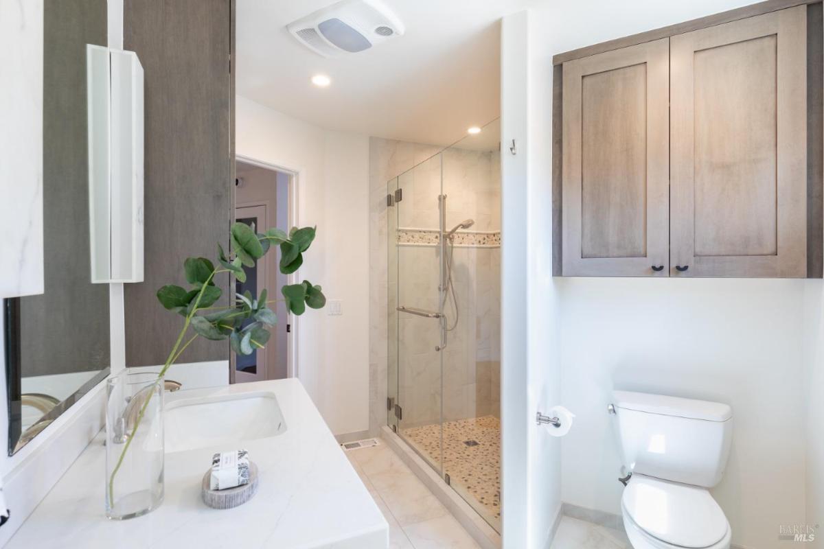 A bathroom with a glass-enclosed shower and a white vanity.