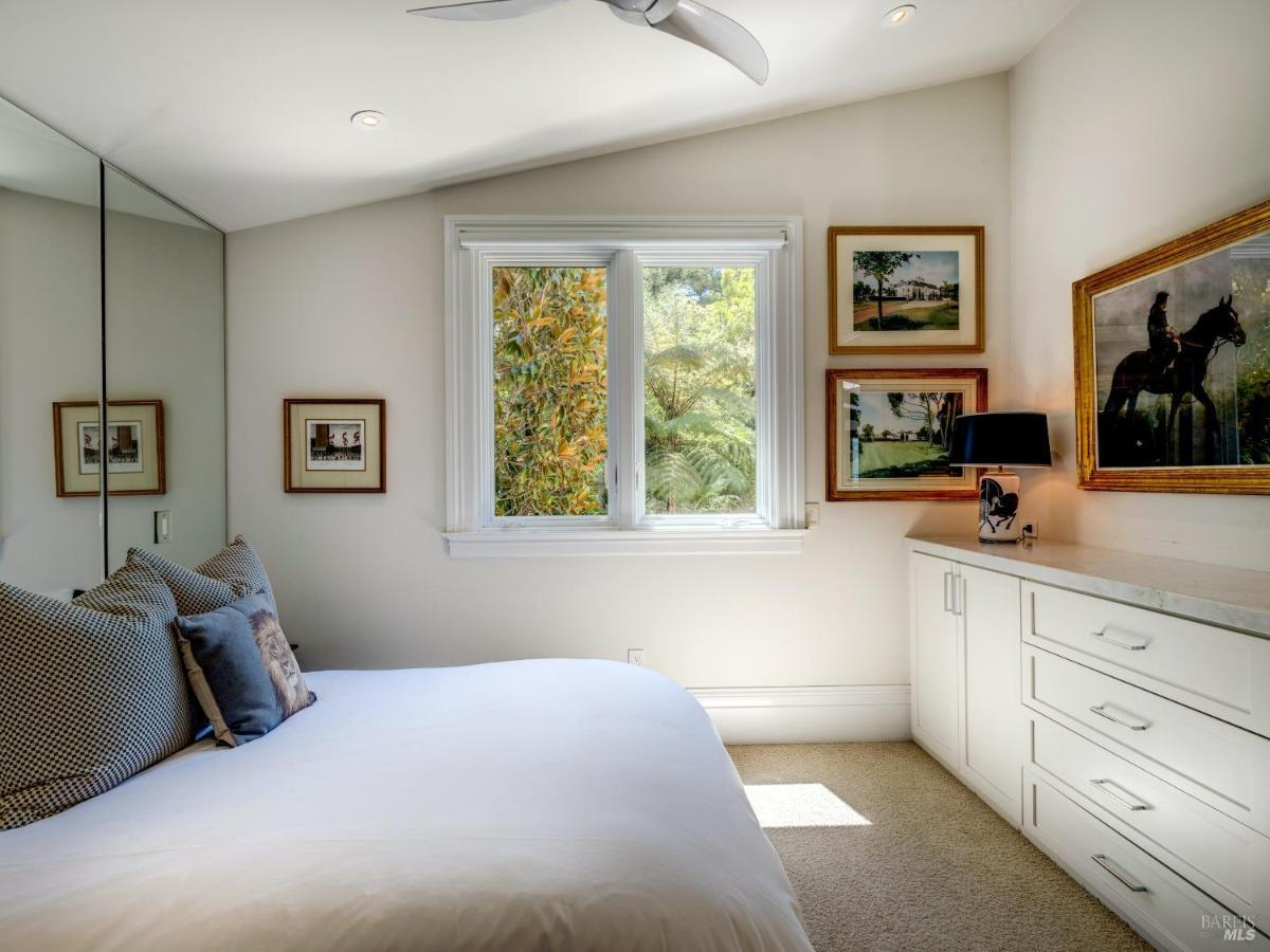 Small bedroom with built-in cabinetry and a window overlooking greenery.