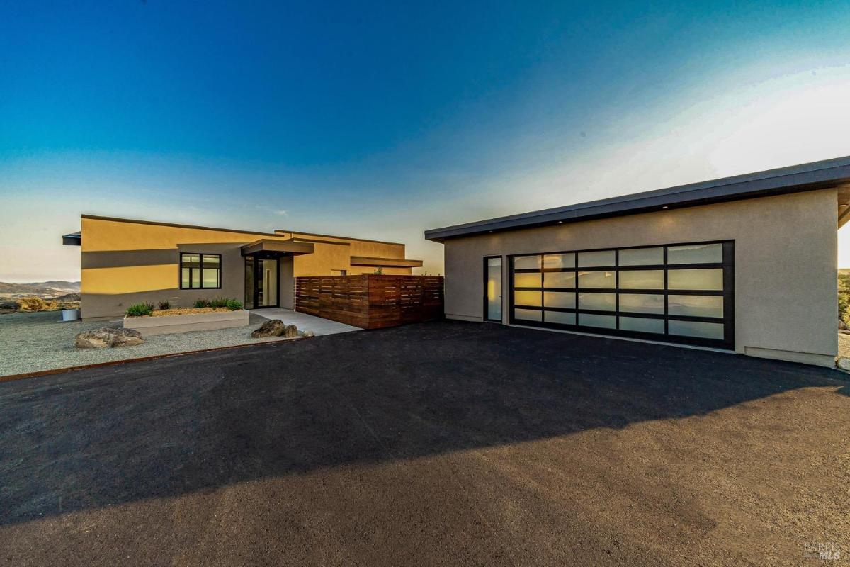 A driveway leading to a modern home with a separate garage.