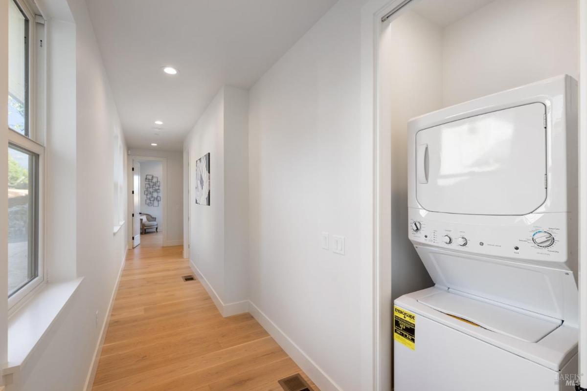 Laundry area with a stacked washer and dryer in a hallway.