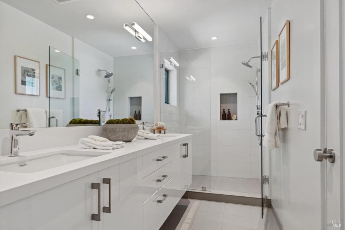 Bathroom with glass shower, double vanity bathroom with a glass-enclosed shower and white fixtures.