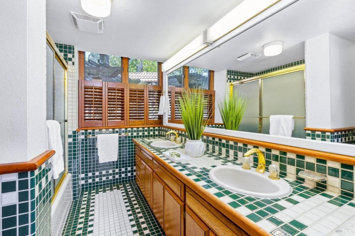 Bathroom featuring green and white tiled counters with dual sinks.